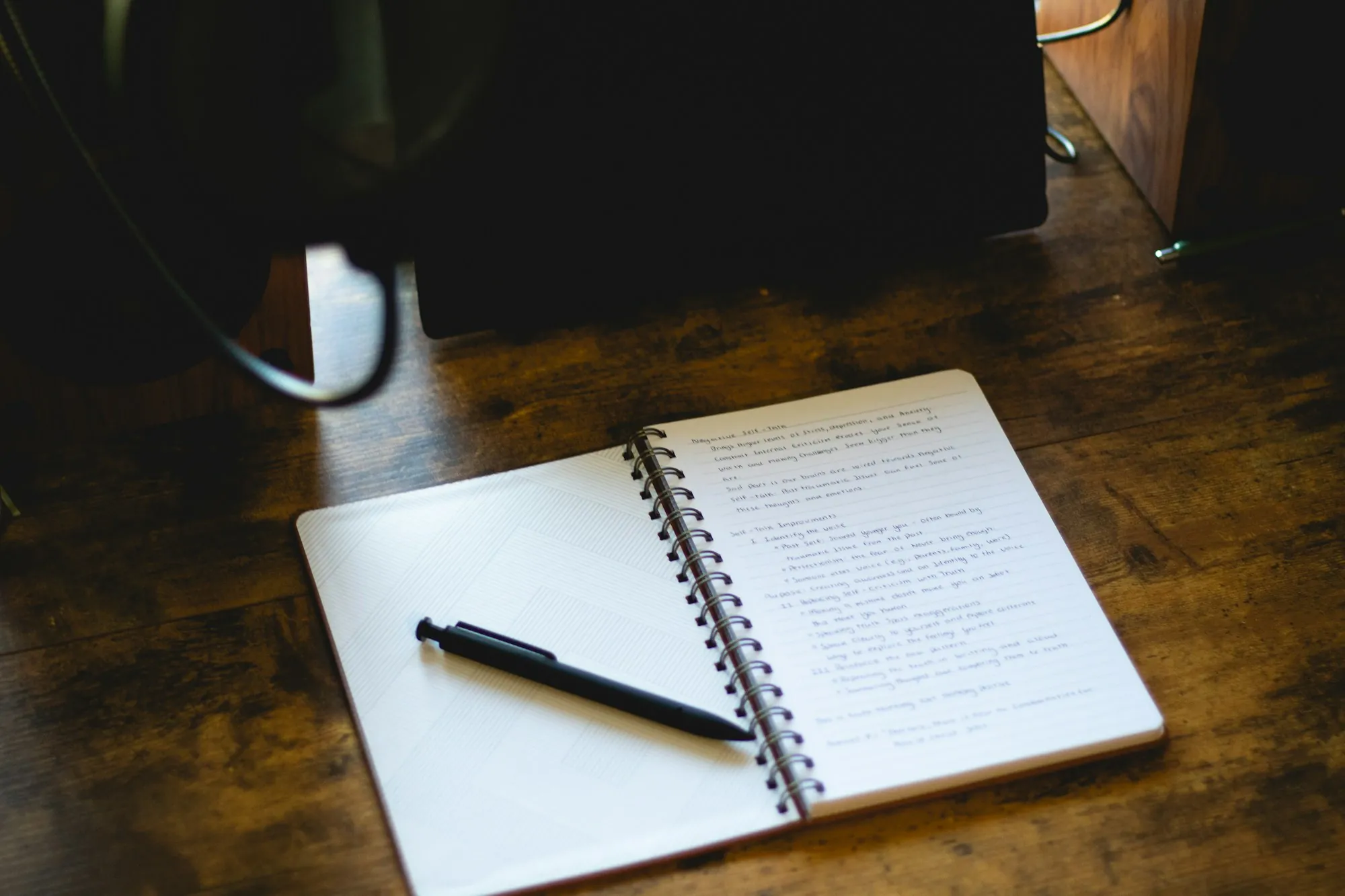 An open notebook and pen on a wooden desk