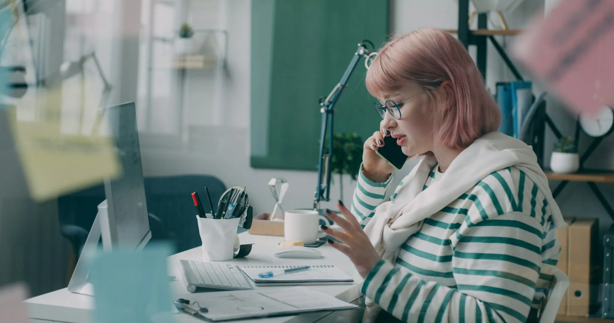 A woman taking a call at a tidy desk