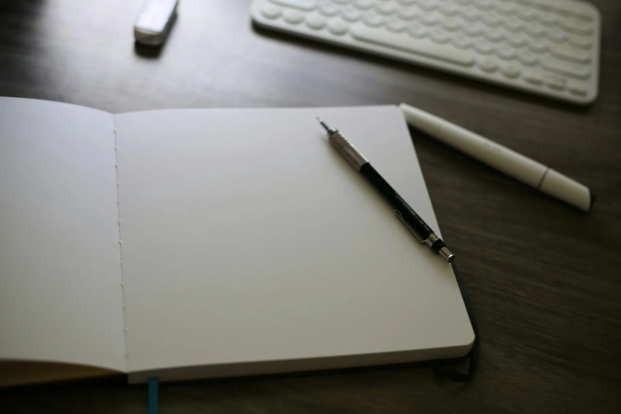 An open notebook on a desk beside a keyboard