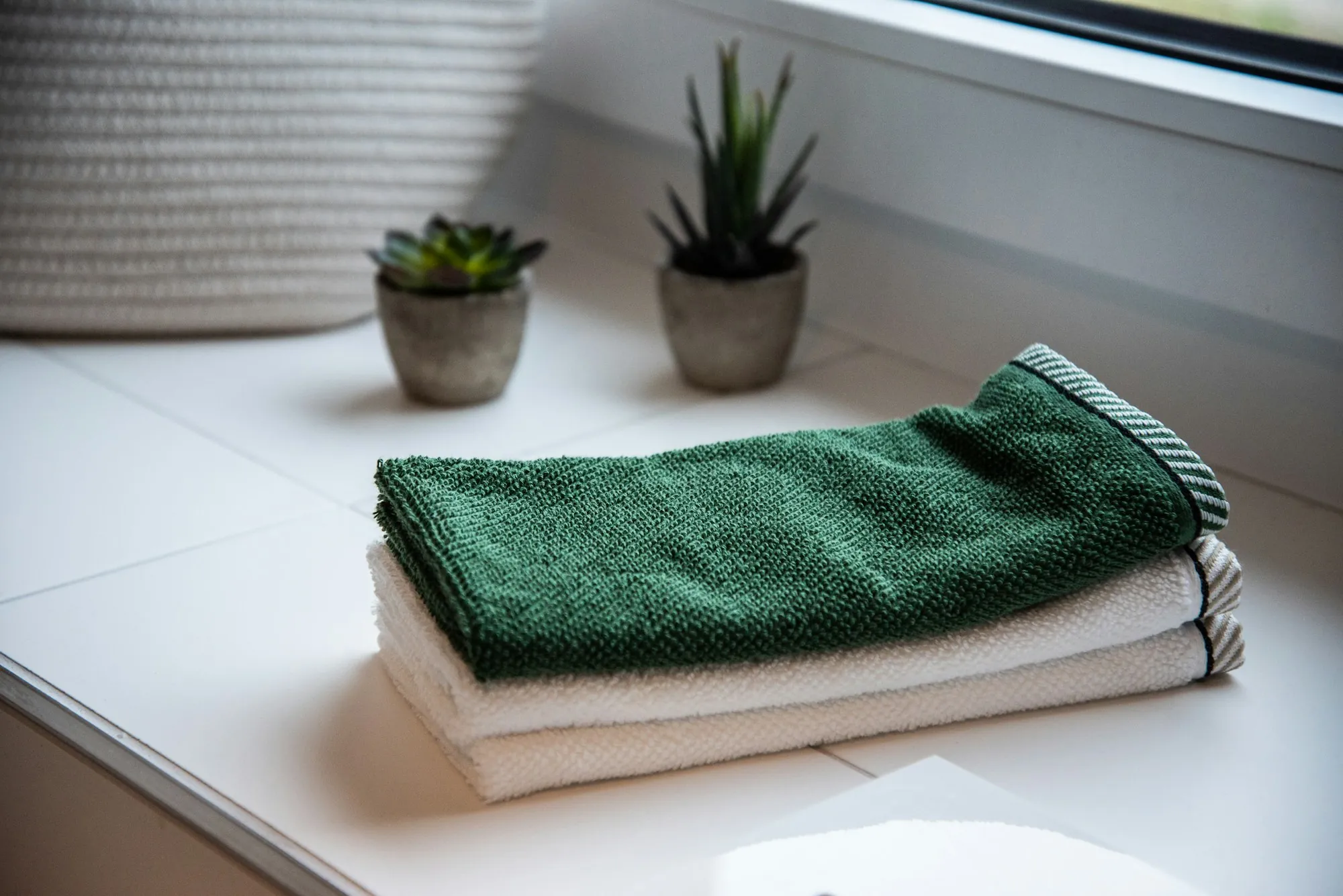 Folded towels beside potted plants in a bathroom