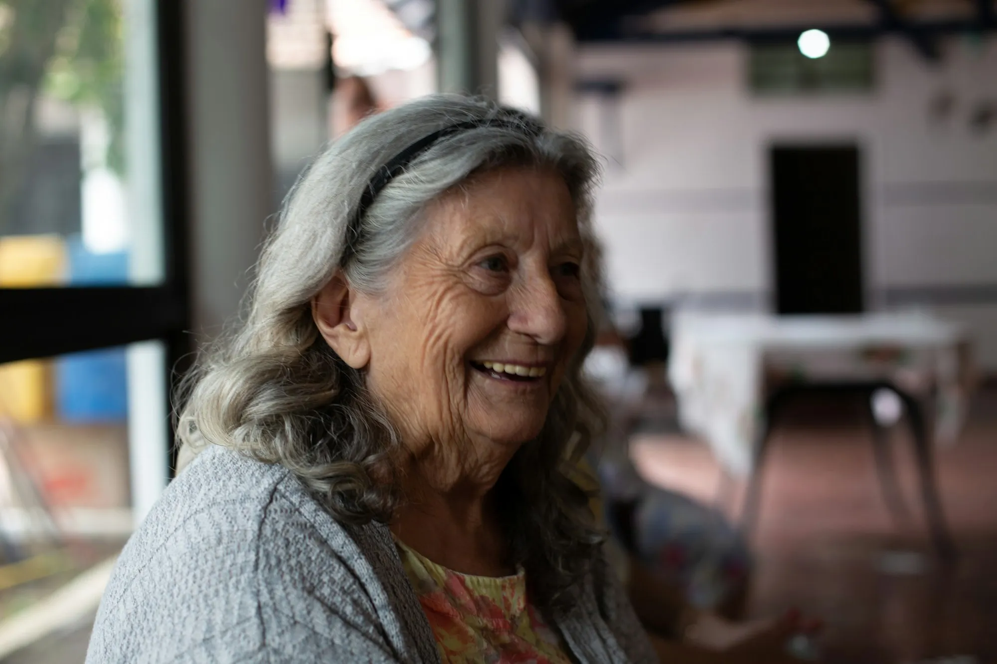 An older woman in a cardigan smiling at home